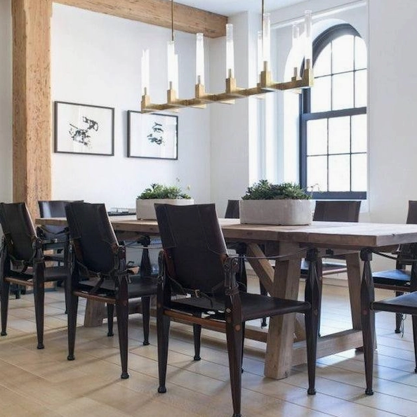 Modern linear glass chandelier with brass finish over casual dining area wood table