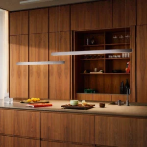 Contemporary linear pendant lamp installed above wooden kitchen island with warm lighting