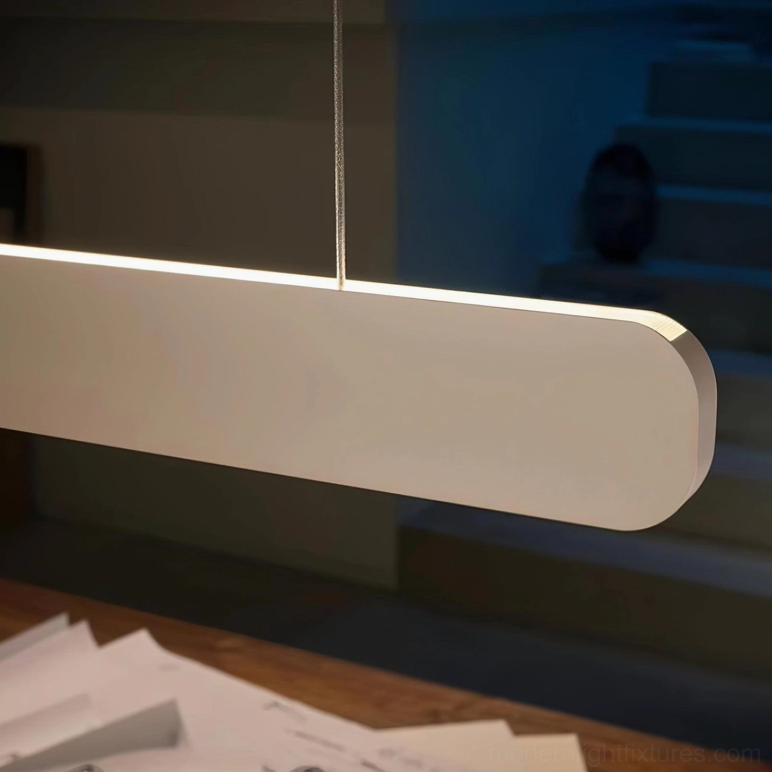 Linear pendant light creating visual interest in large open plan dining and kitchen zones