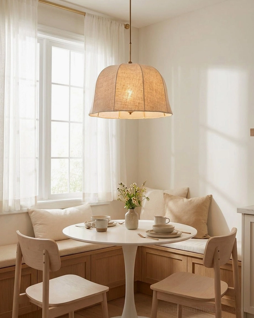 Beige linen pendant light over dining banquette seating with sheer window curtains, cozy warm neutral interior ambiance