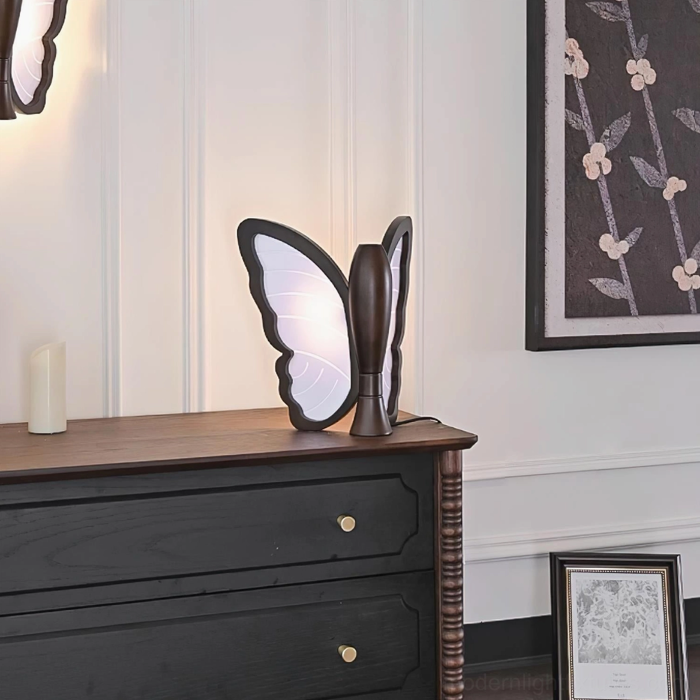 Butterfly table lamp illuminated on black wooden dresser showing glowing wings and ambient lighting effect