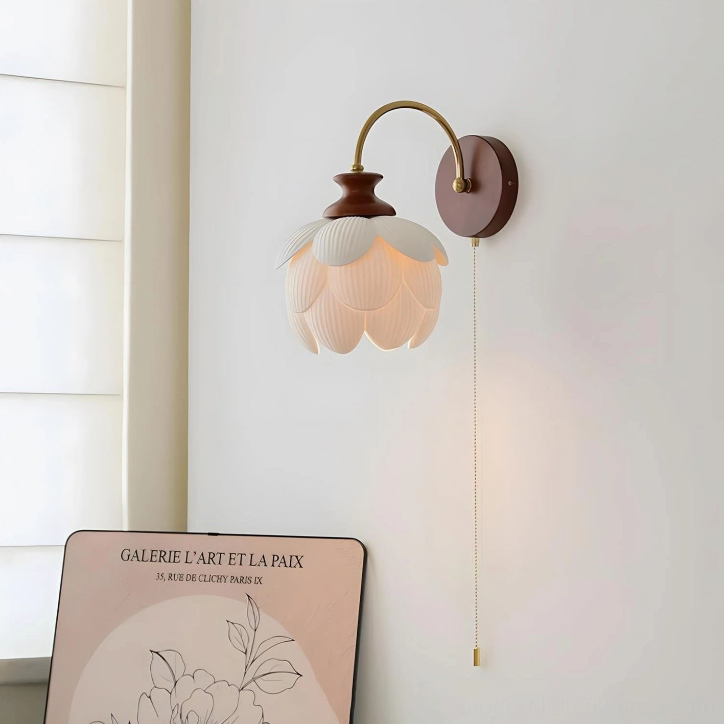 Illuminated porcelain lotus wall sconce casting warm amber light and shadow patterns on interior wall with art print
