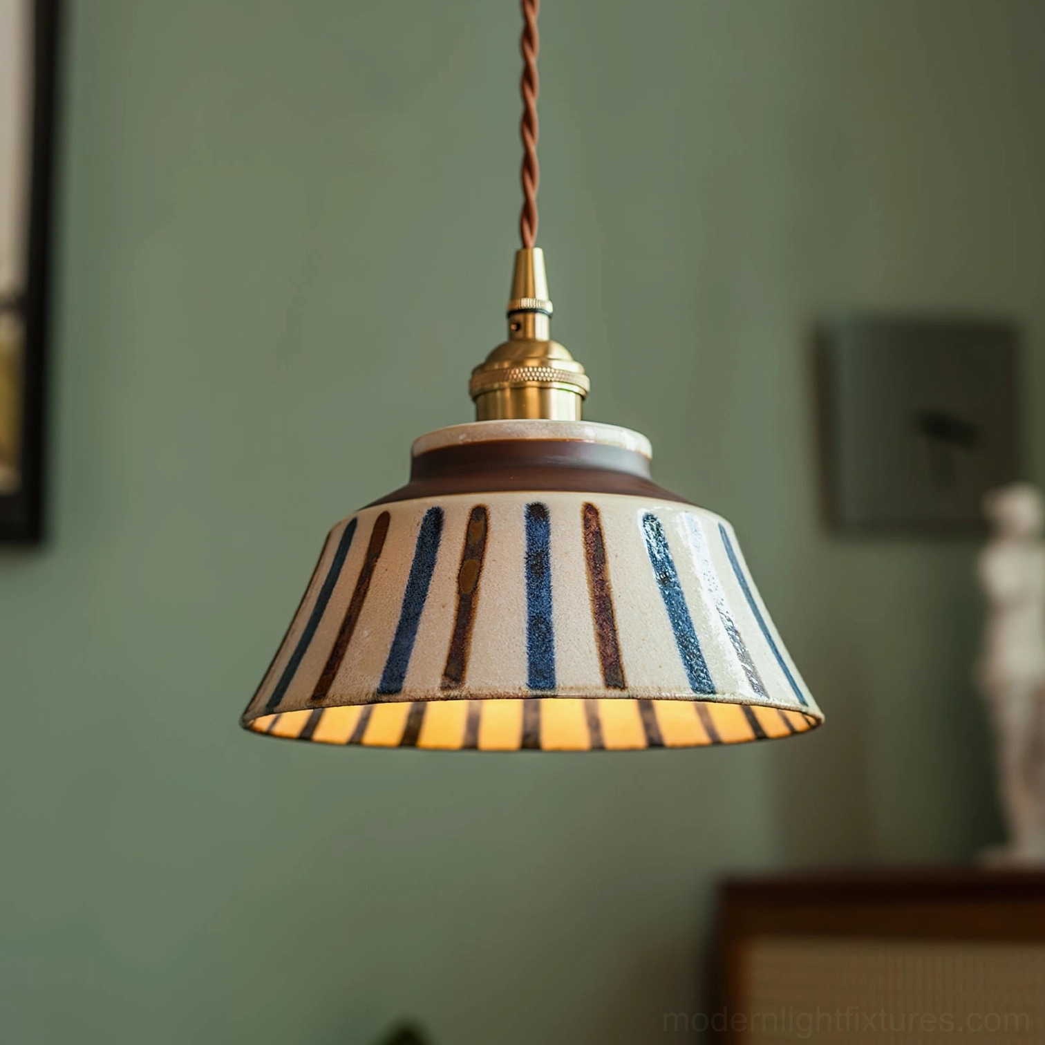 Illuminated ceramic pendant light with striped hand-painted shade casting warm glowing light indoors