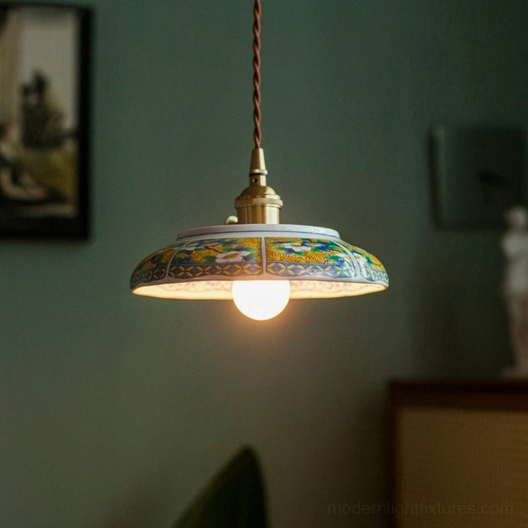 Lit ceramic saucer pendant light with warm filament bulb visible below shallow shade, creating downward glow