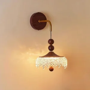 Illuminated crystal wall sconce displaying warm white 3000K LED lighting with crystal droplet refraction on warm indoor wall