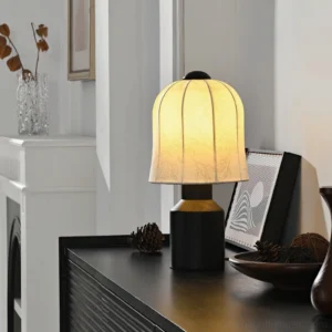 Illuminated botanical table lamp displayed on black sideboard in living room, glowing fabric shade with floral pattern casting warm ambient light