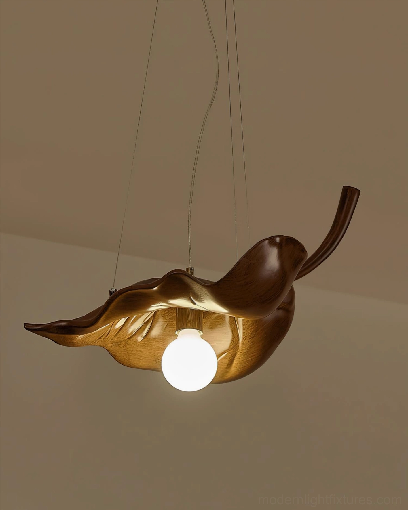 Illuminated maple leaf pendant light with warm glowing bulb, low angle interior perspective