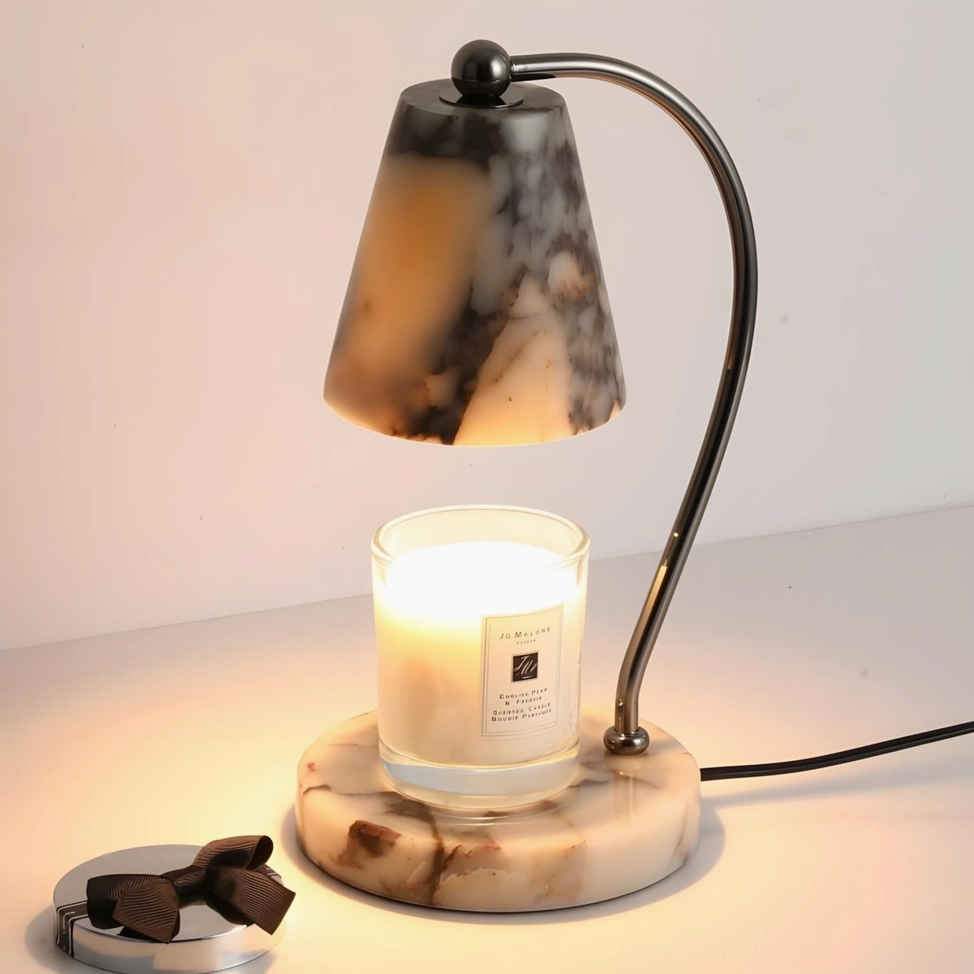 Illuminated modern marble candle warmer lamp close-up with lit scented candle and marble base design
