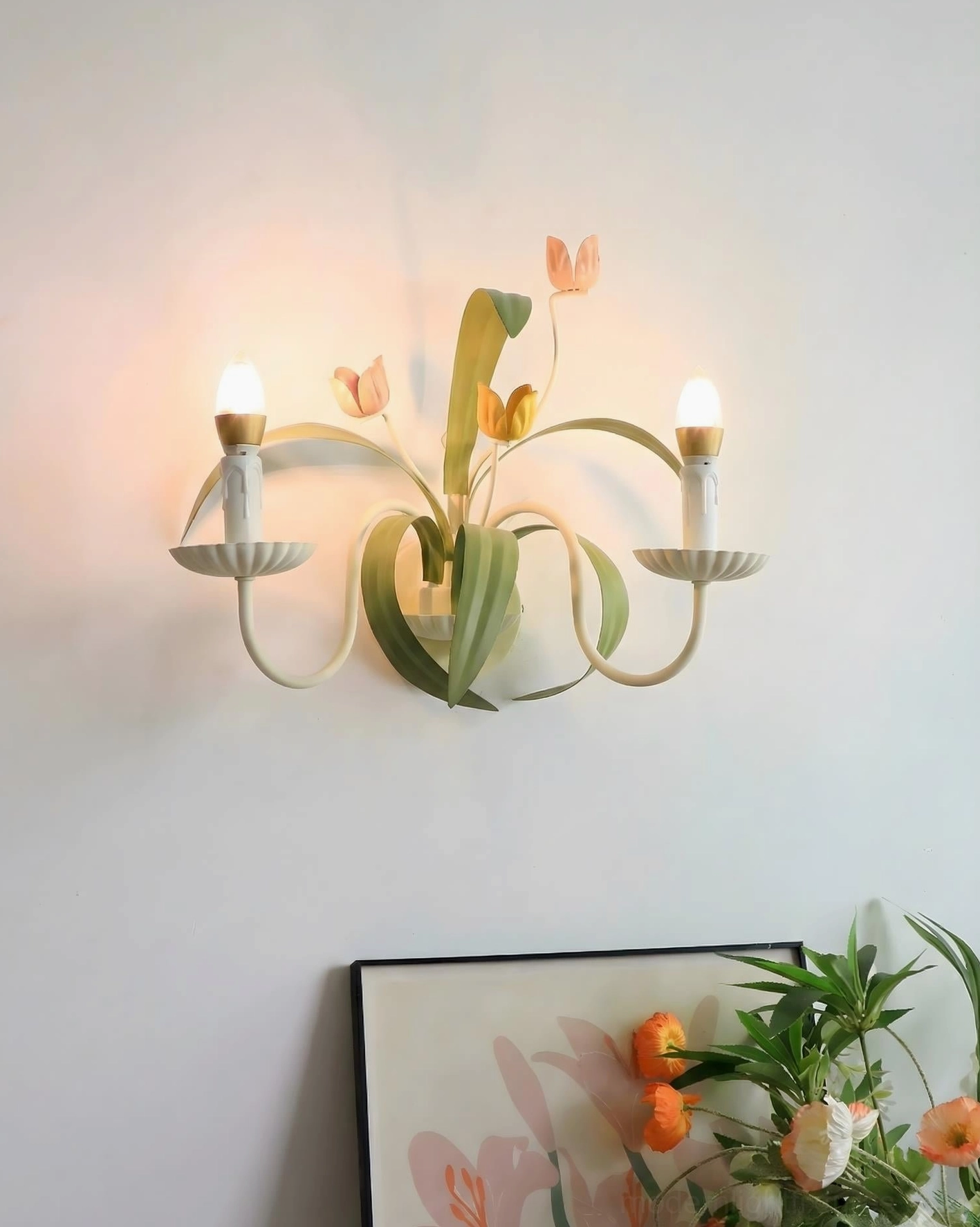 Illuminated botanical tulip wall sconce with lit candle bulbs creating warm glow on cottage core accent wall