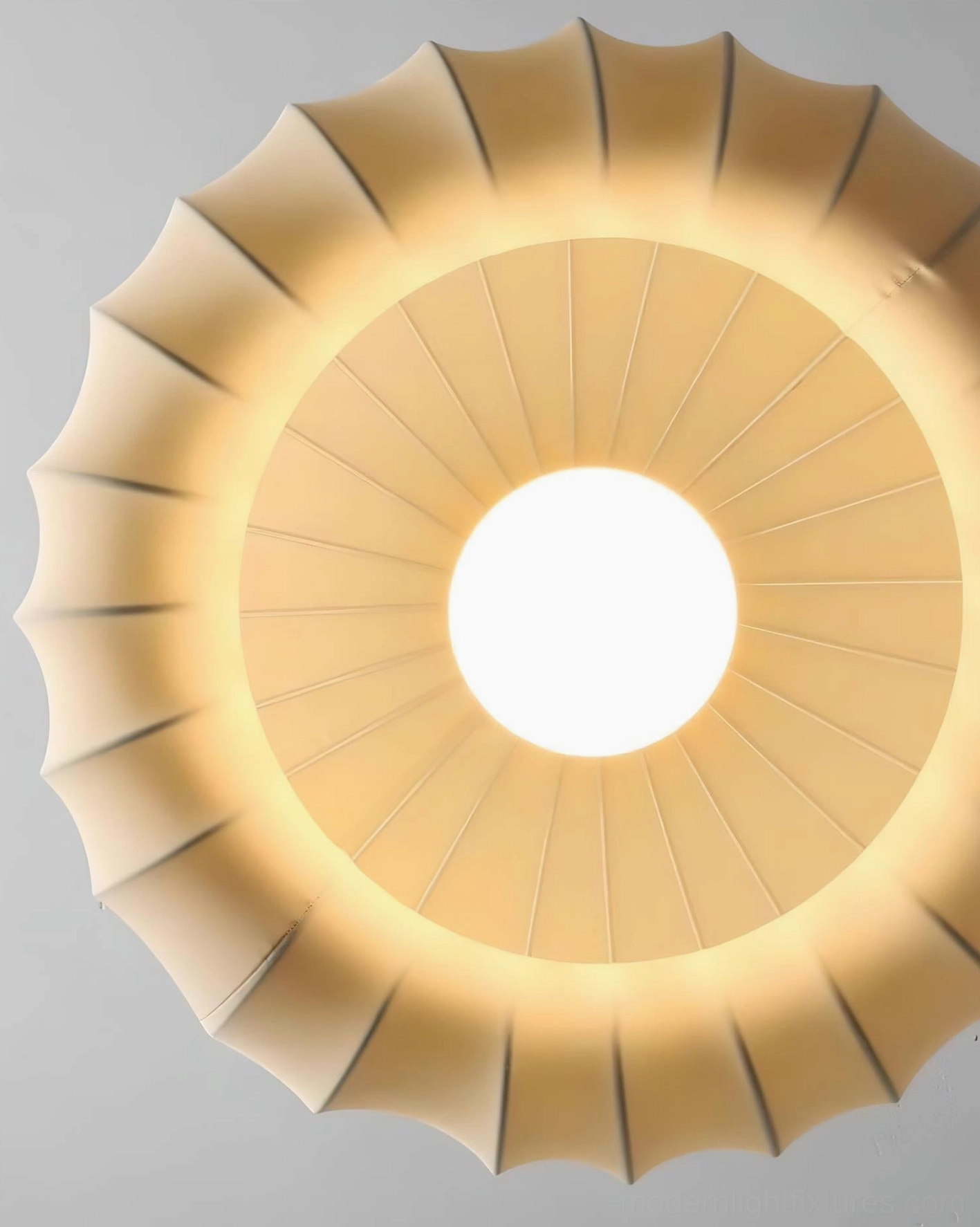 Lotus Belly pendant light bottom-up view showing central light source and radial pleated fabric texture in warm cream tone, diffused lighting effect