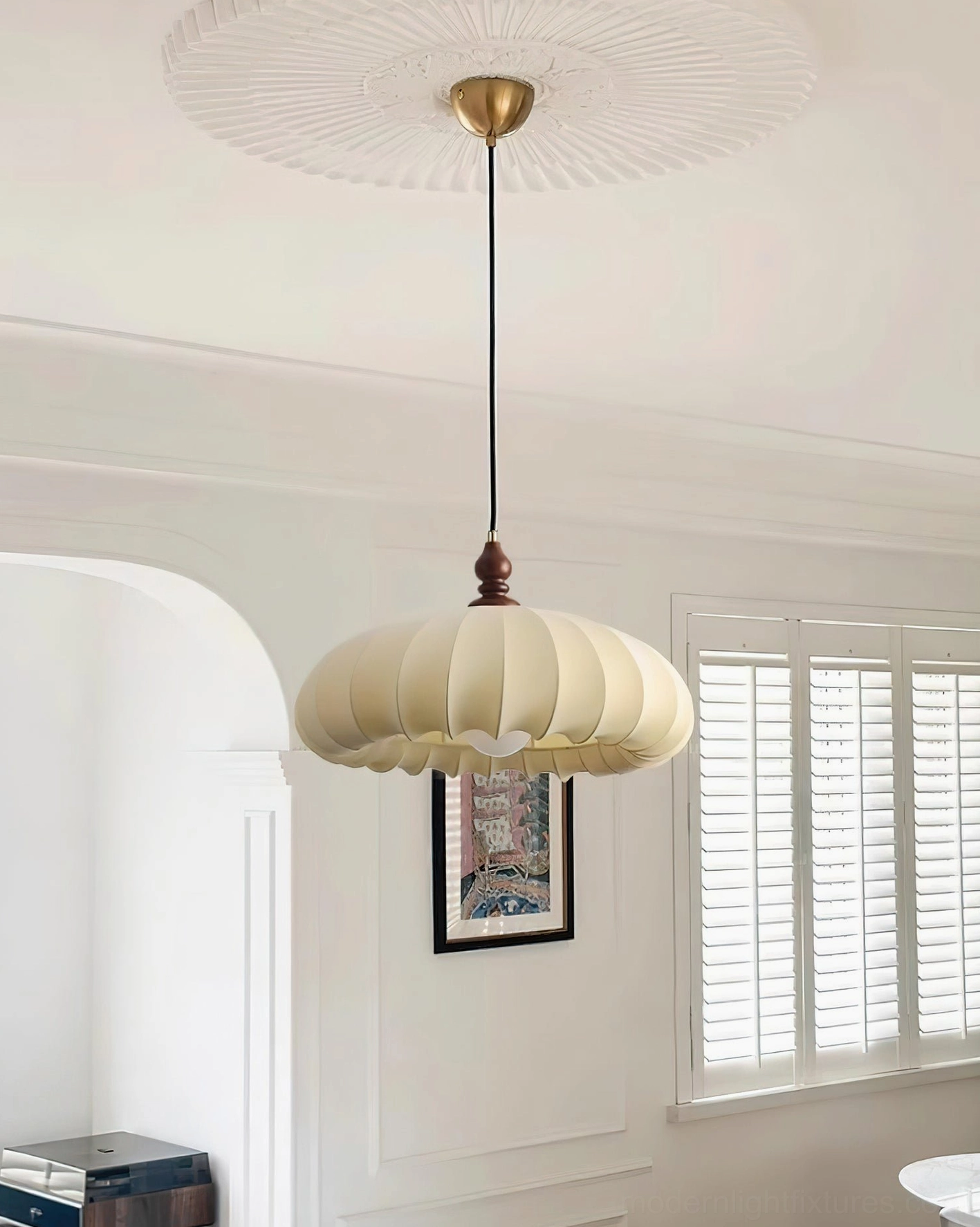 Lotus Belly pendant light hung in French-style living room with arched doorway and shutters, overhead perspective showing pleated shade and warm neutral decor coordination