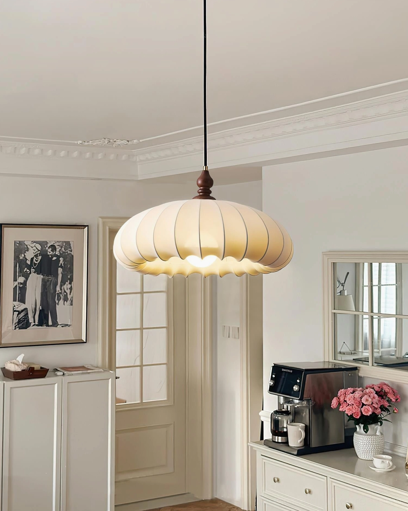 Illuminated Lotus Belly pendant lamp in retro American style kitchen dining area, low-angle front view showing glowing cream fabric shade and wooden joint detail