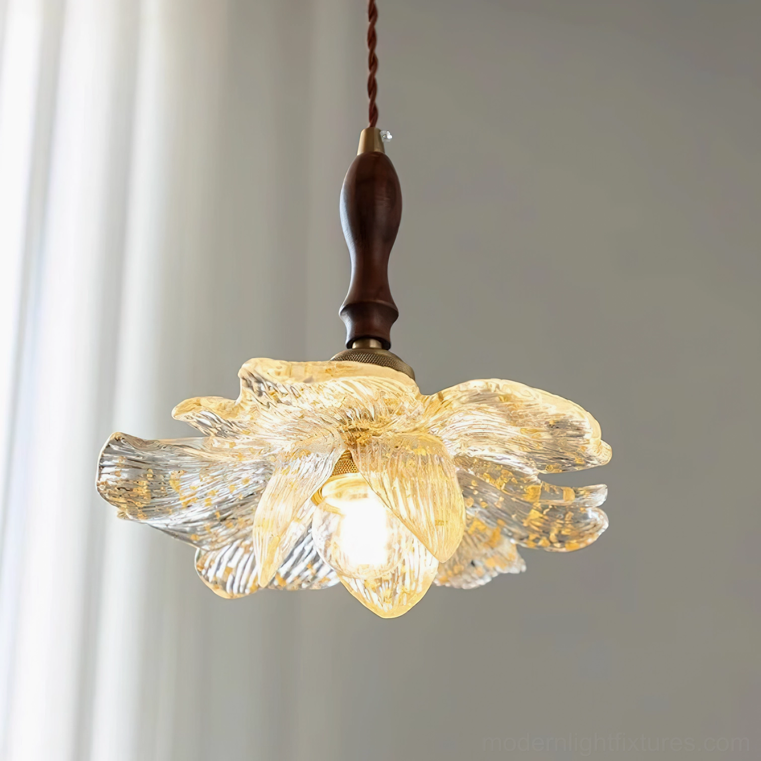 Illuminated lotus pendant light hanging indoors with warm glow and sheer curtain backdrop