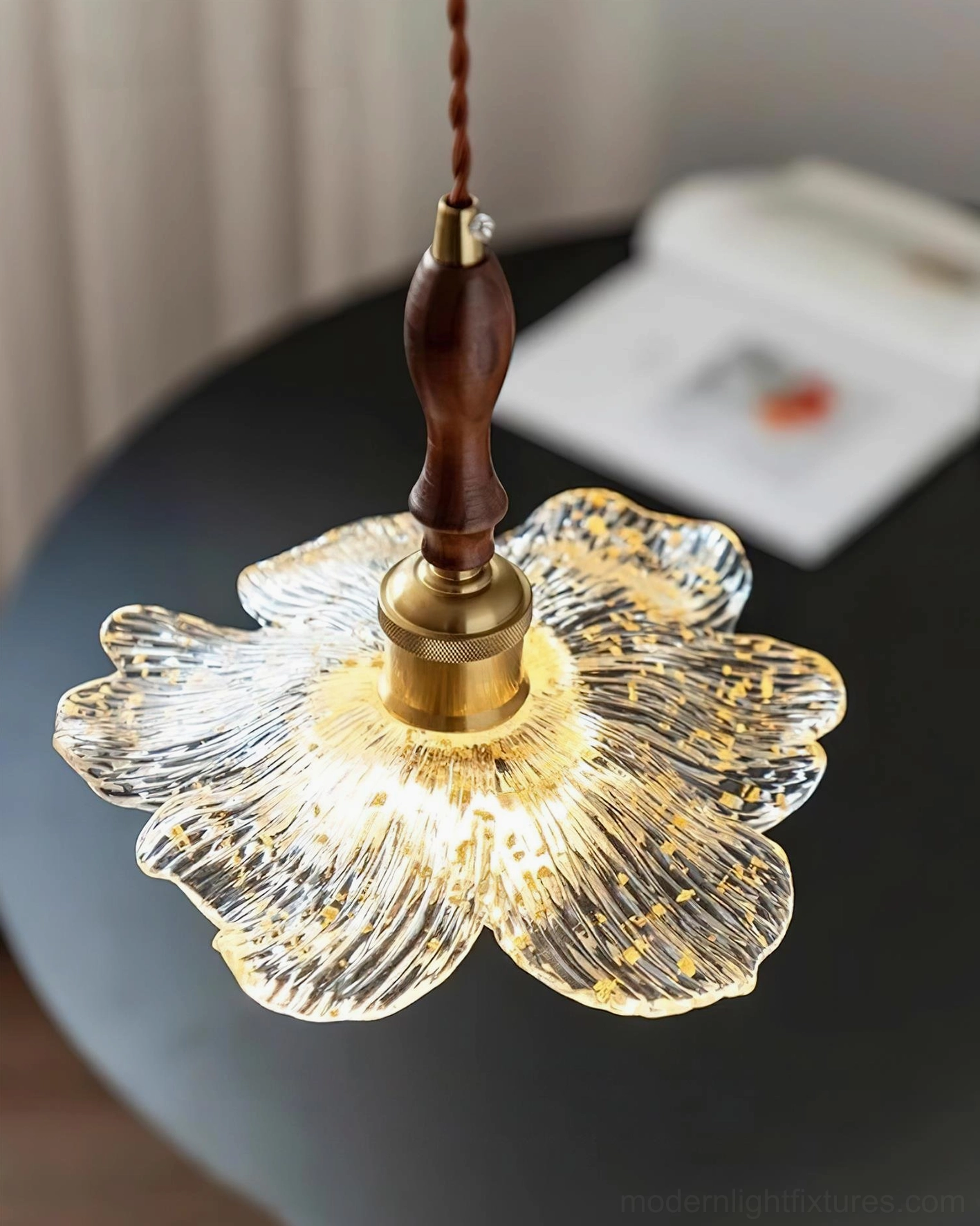 Close-up detail of lotus pendant light with brass hardware and illuminated rippled glass