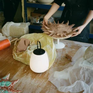 Overhead view of Lucca rechargeable table lamp on wooden workbench in ceramic art studio setting