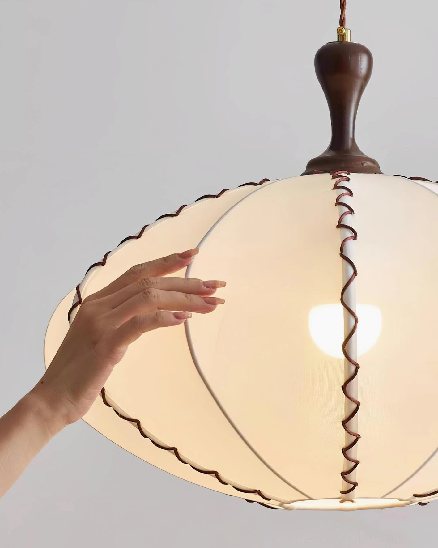 Lucian pendant light close-up showing illuminated interior, fabric shade, and walnut trim detailing