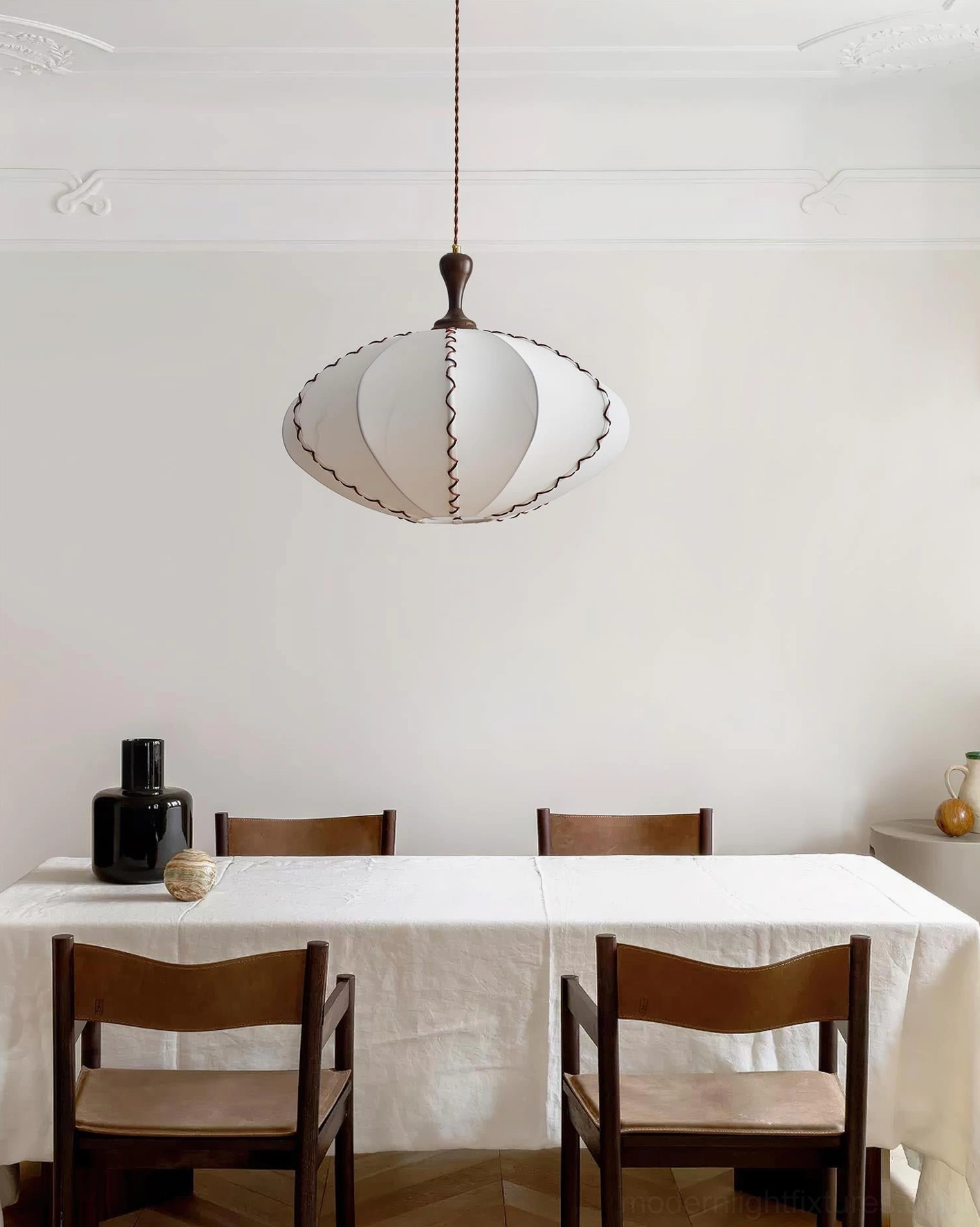Lucian scalloped fabric pendant lamp suspended above dining table with wooden chairs in residential dining room