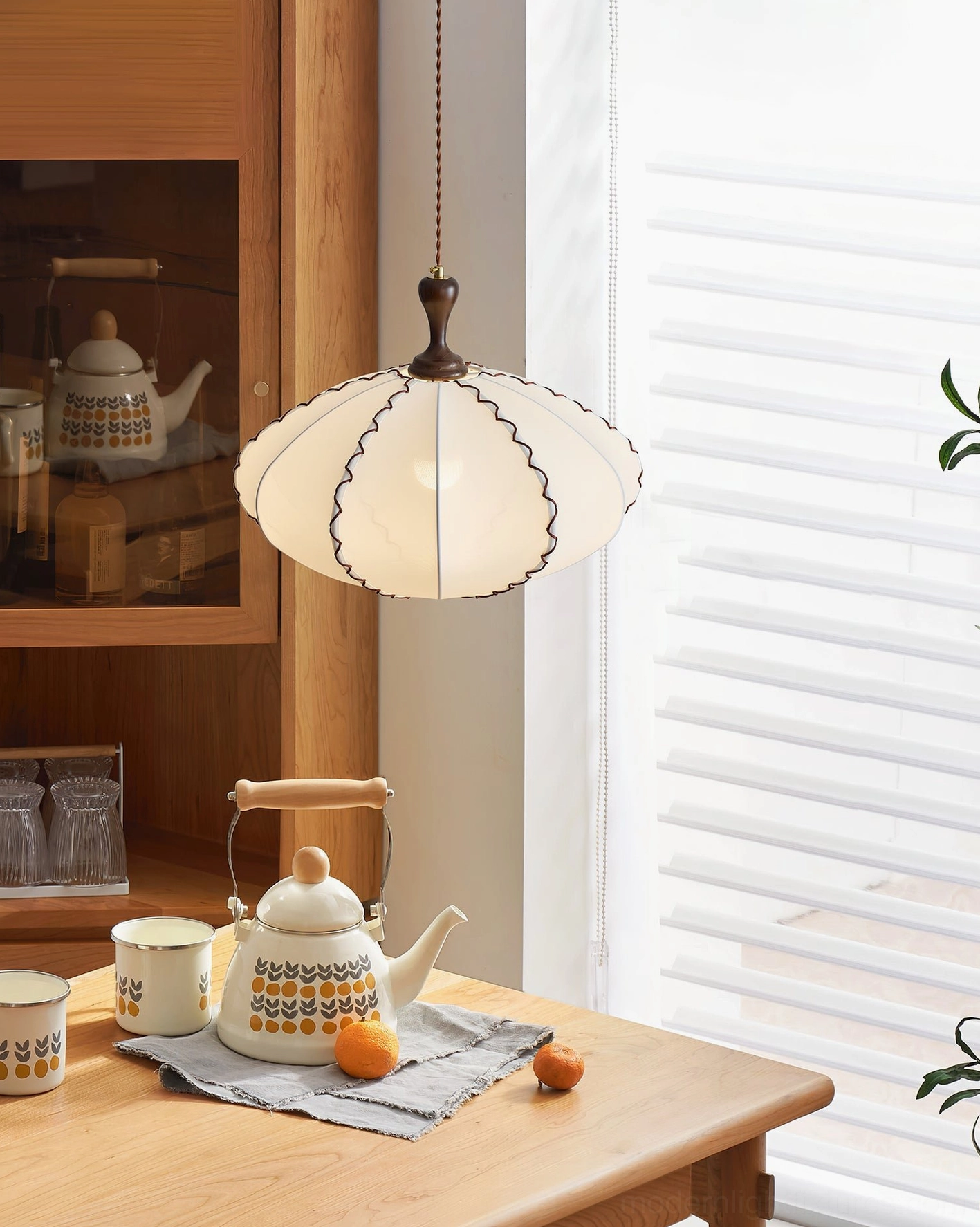 Lucian fabric pendant lamp hanging above kitchen dining nook table with tea service and wooden furnishings