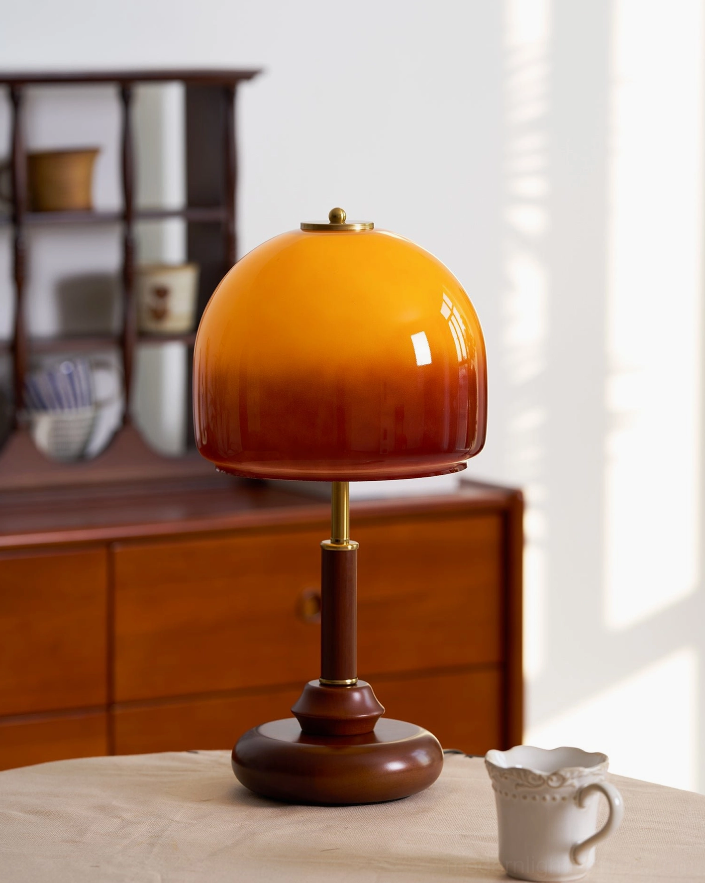 Gradient amber glass dome lamp on wooden dining surface, side view showing mid-century modern style and warm lighting