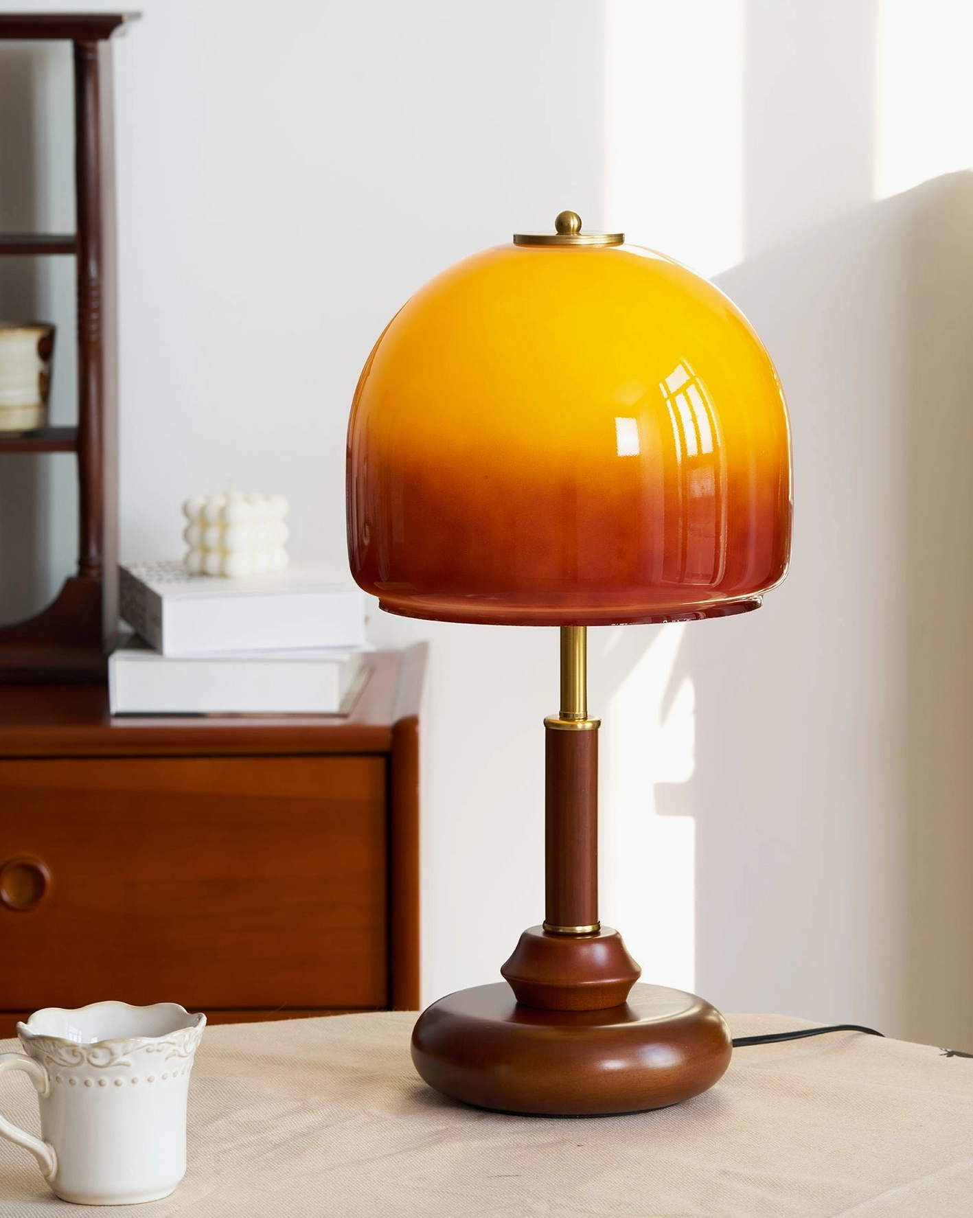 Mid-century modern Luciano table lamp positioned on dining table with wooden cabinet backdrop and ceramic decor