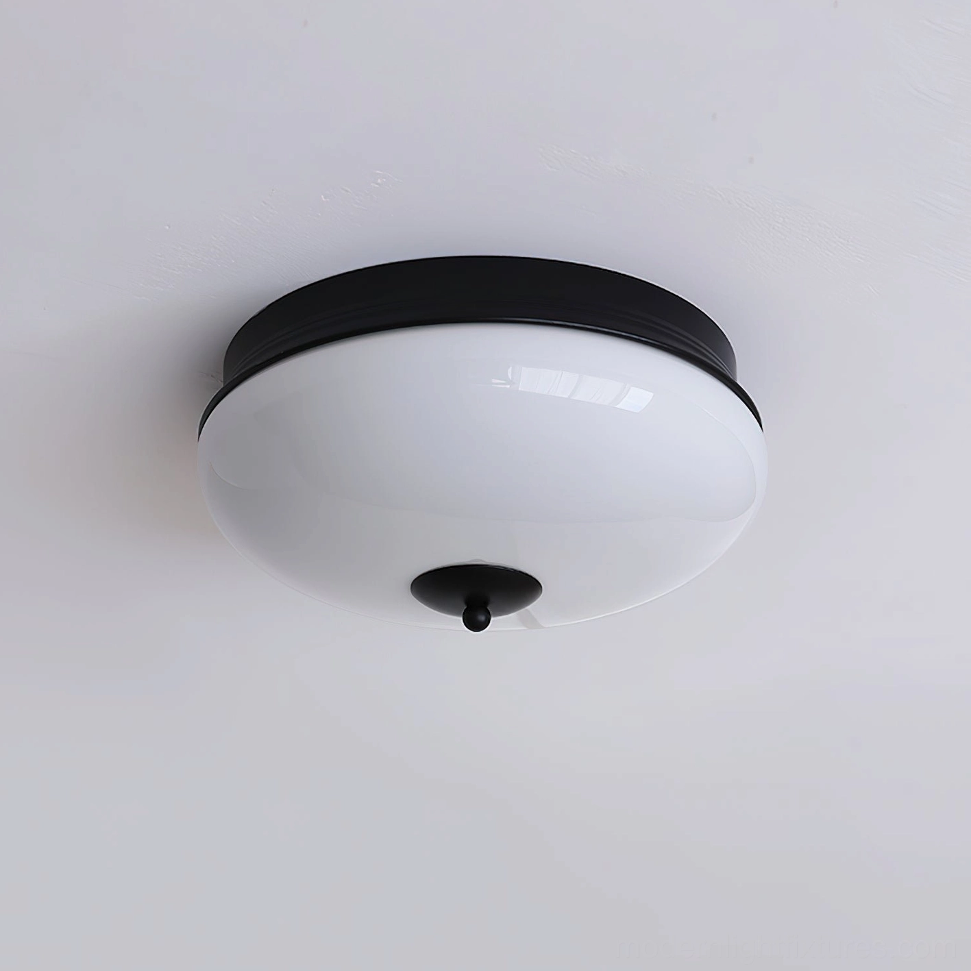 Ludo round flush mount with matte black finish and white frosted glass shade, studio view