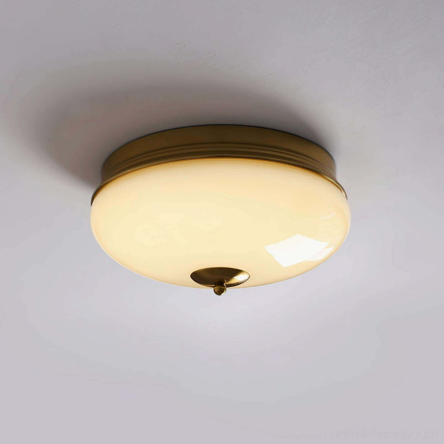 Ludo brass trim ceiling fixture mounted on ceiling with warm glowing light output, side view