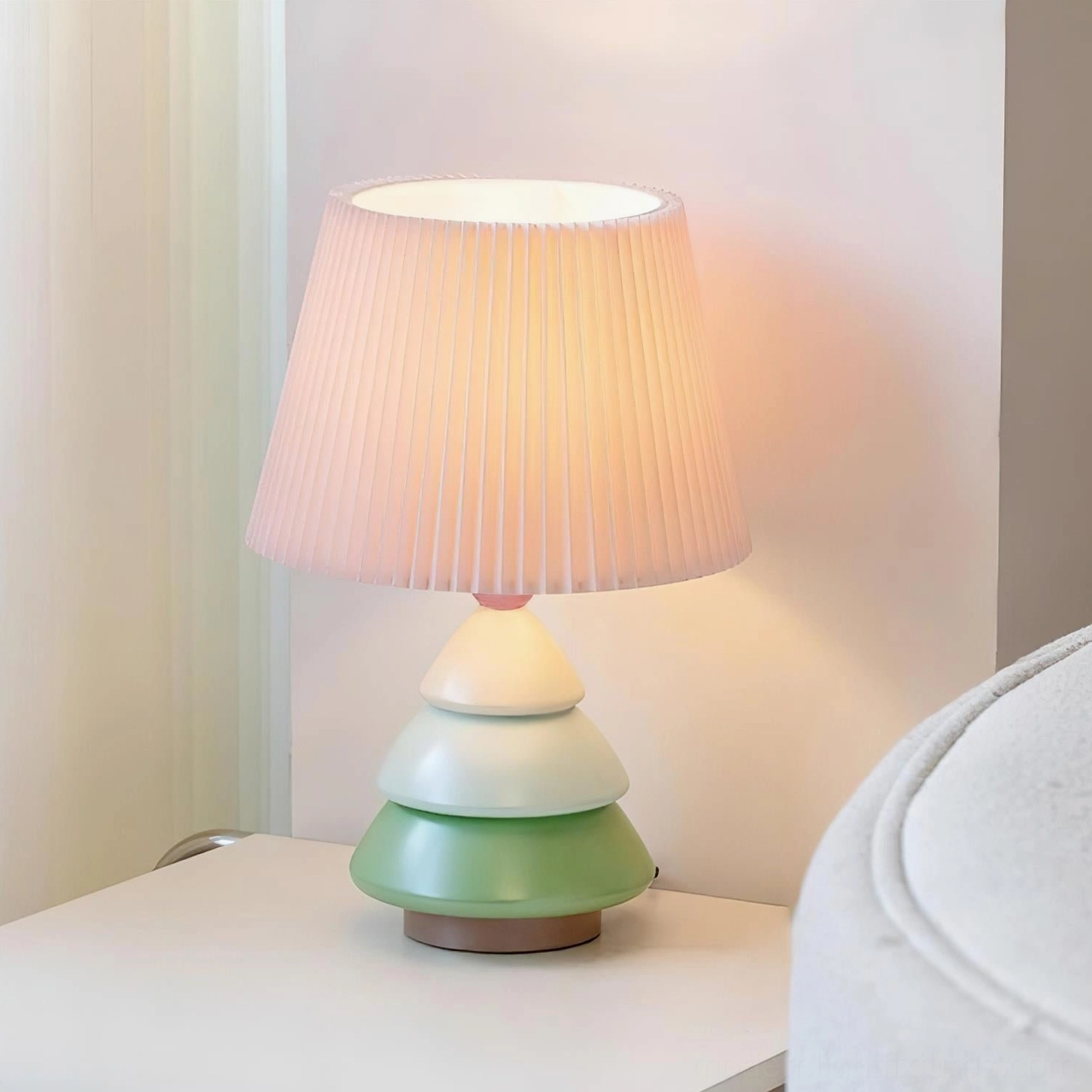 Luma Globe sculptural table lamp side view showing tiered resin base and pleated fabric shade with wall wash effect