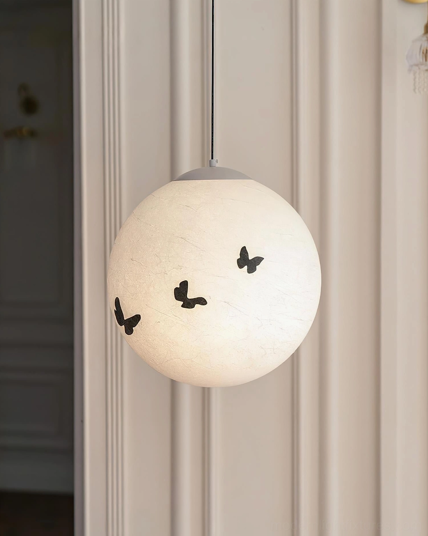 Luna Flutter butterfly pendant lamp lit in warm beige with black butterfly cutouts, glowing illumination detail