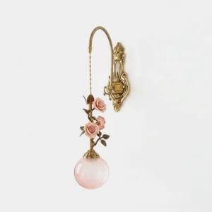 Lunafleur brass wall sconce with porcelain rose details and pink frosted glass globe front view studio shot