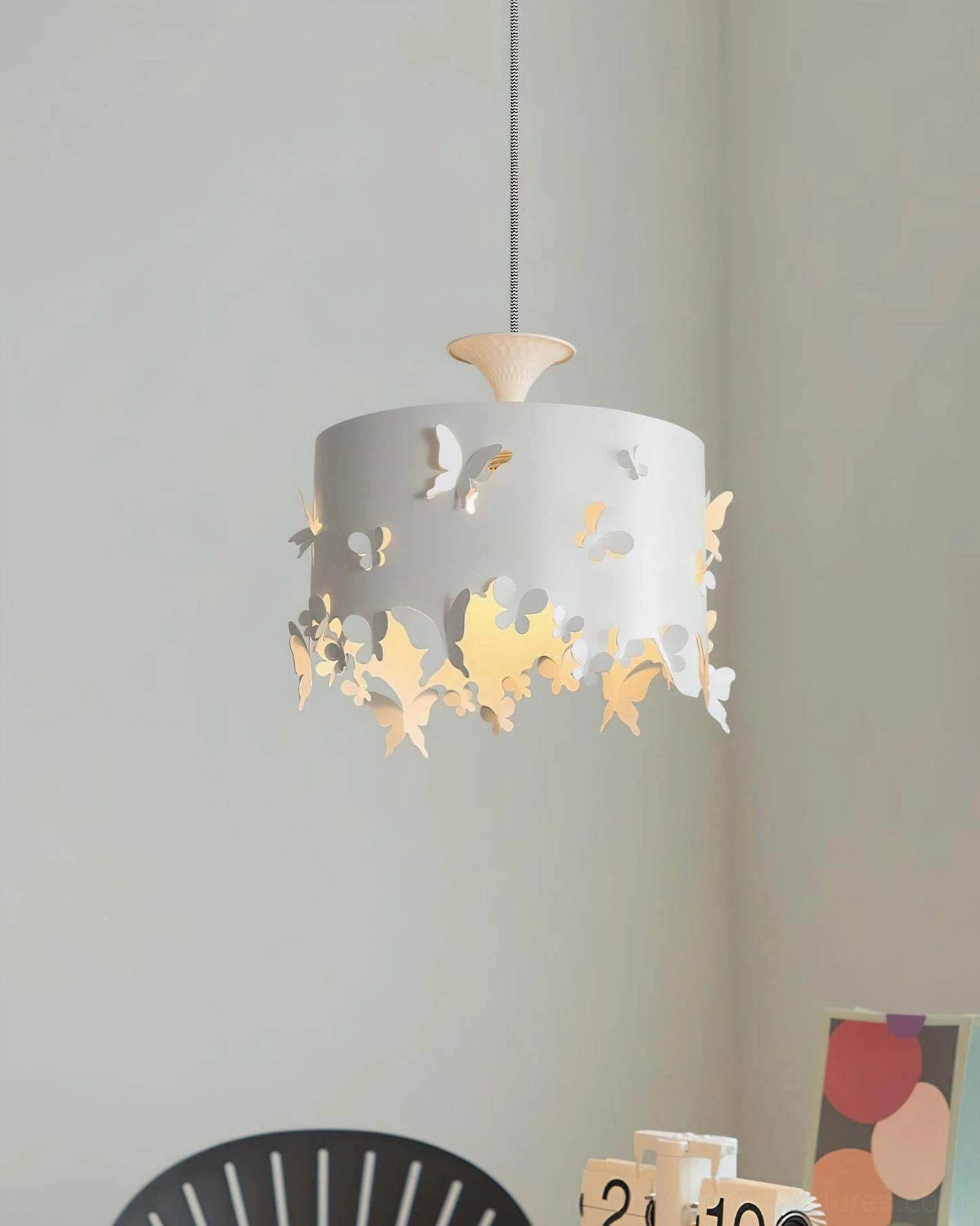 Butterfly pendant light illuminated in home office desk corner with warm glow and visible 3D butterfly embossed details