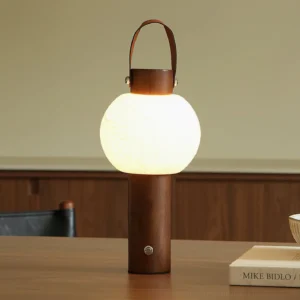 Lunero walnut portable table lamp glowing warm white 3000K LED light on wooden surface with book