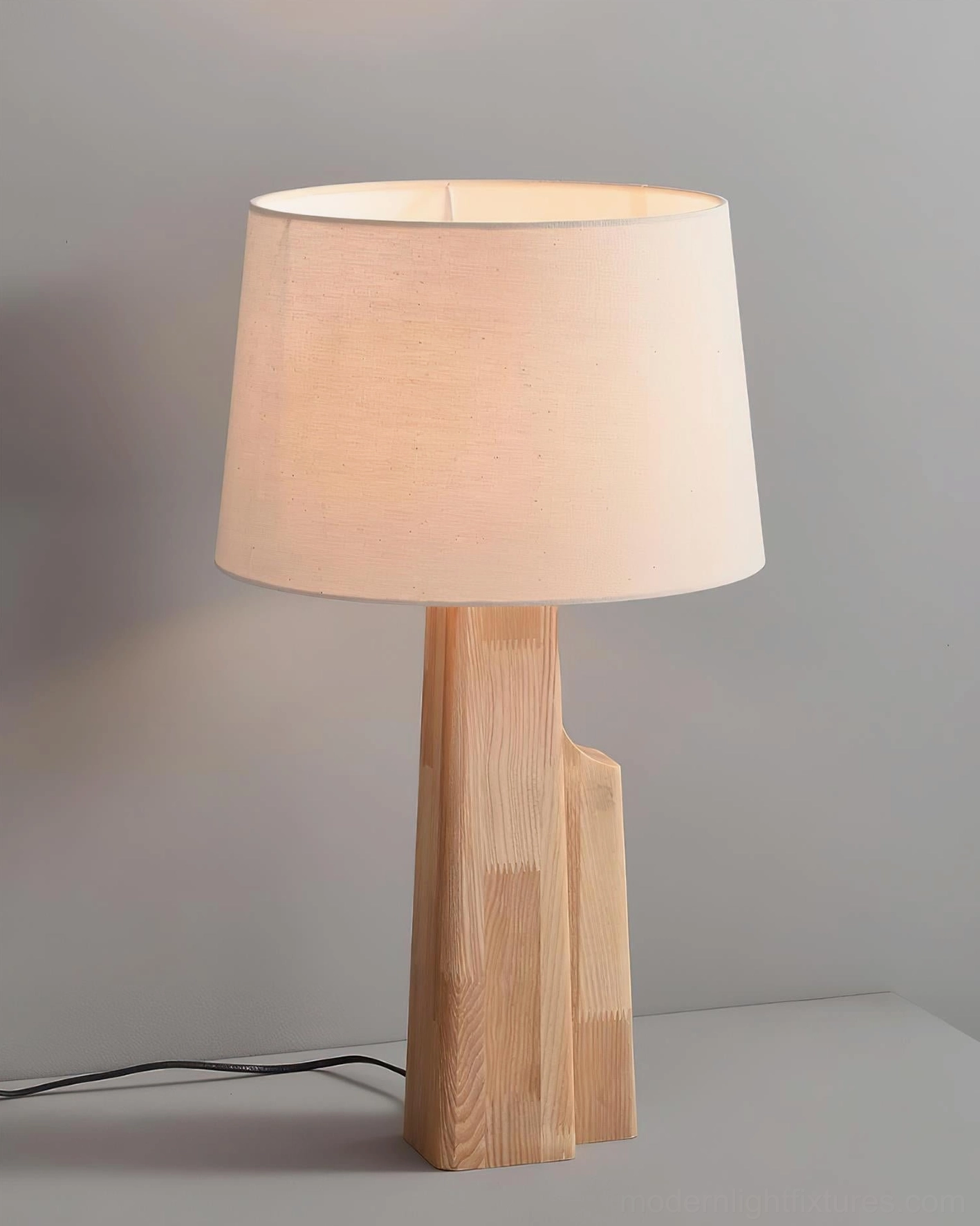 Lunet table lamp with beige fabric lampshade and stepped wood base in studio three-quarter view