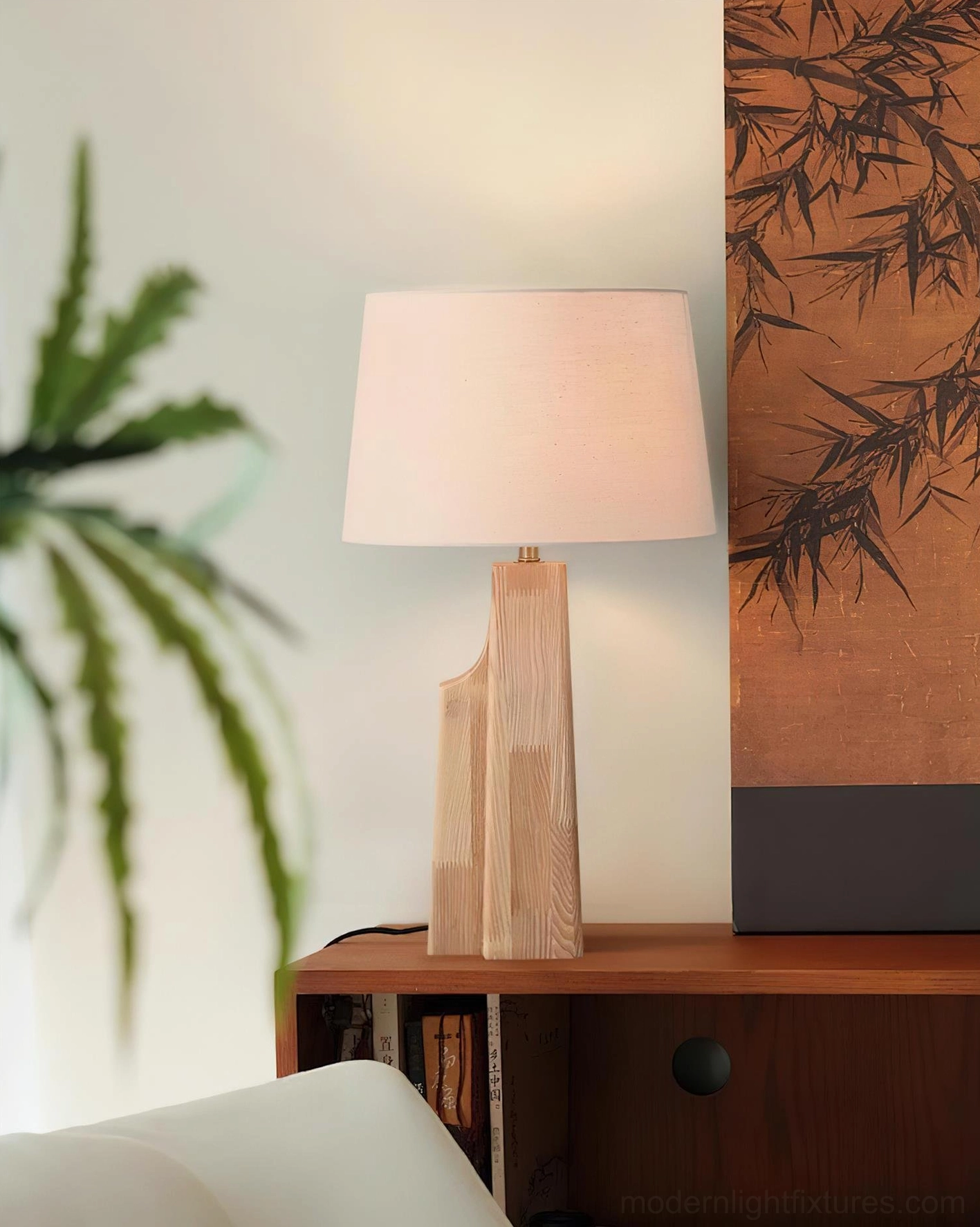 Lunet table lamp on wooden cabinet with glowing warm light and bamboo wall decor in living room