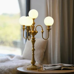 Modern brass candlestick table lamp with 5 frosted glass heads displayed on luxury living room side table