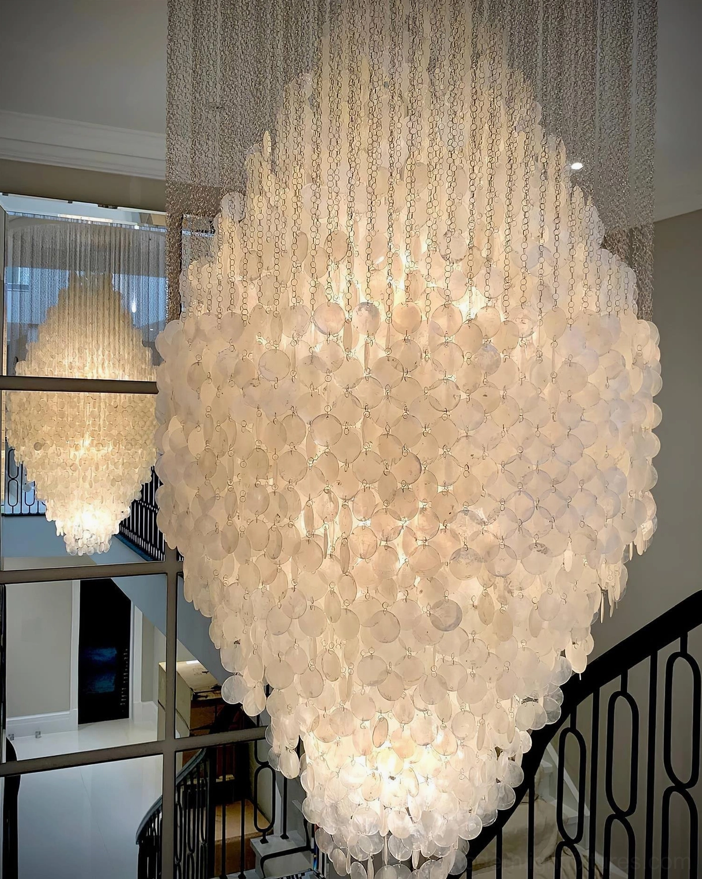 Modern capiz shell chandelier installed in luxury apartment foyer with high ceiling and elegant finishes
