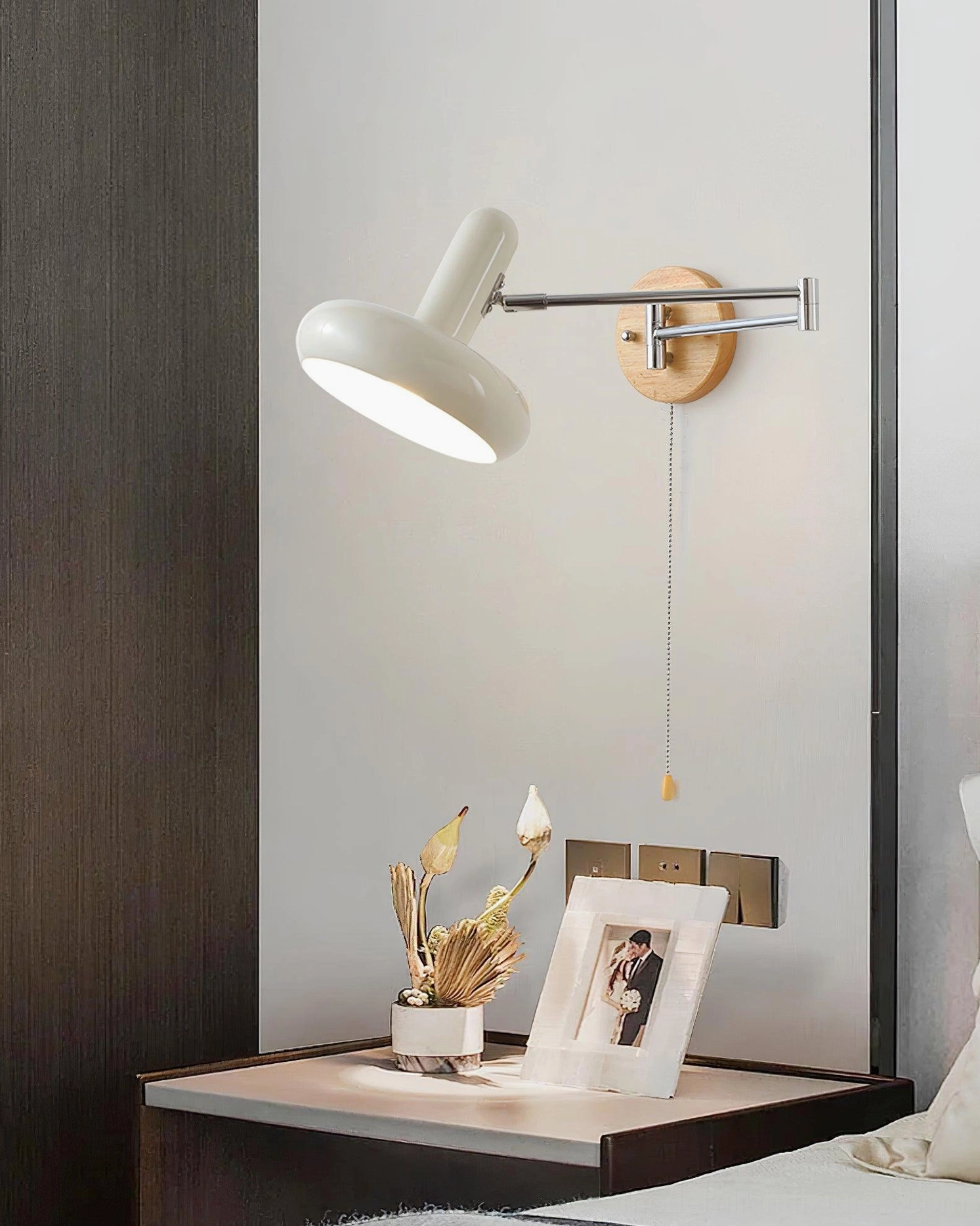 Maddie wall sconce in bedroom interior with decorative bedside table featuring dried flowers and photo frame