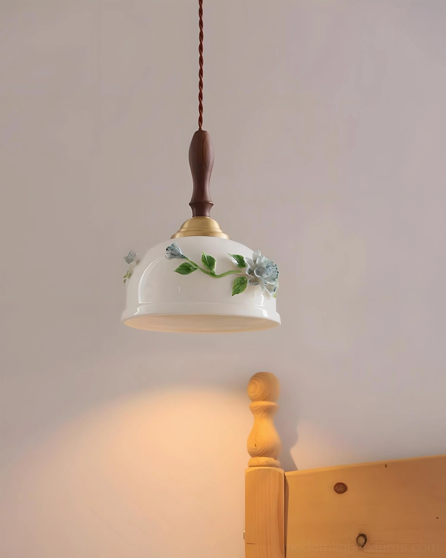 Maelis ceramic pendant light glowing above wooden bed headboard, creating intimate warm illumination in contemporary bedroom interior