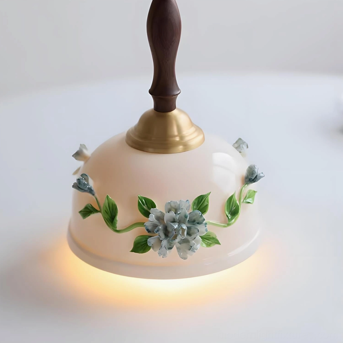 Maelis ceramic pendant lamp upward close-up view from below dining table, glowing warm light illuminating hand-painted botanical details