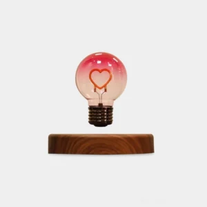 Heart-shaped magnetic levitating table lamp with warm LED filament floating above walnut wooden base on white background