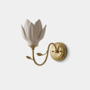 Magnolia bud ceramic wall sconce with white layered petals and brass curved arm, frontal studio view