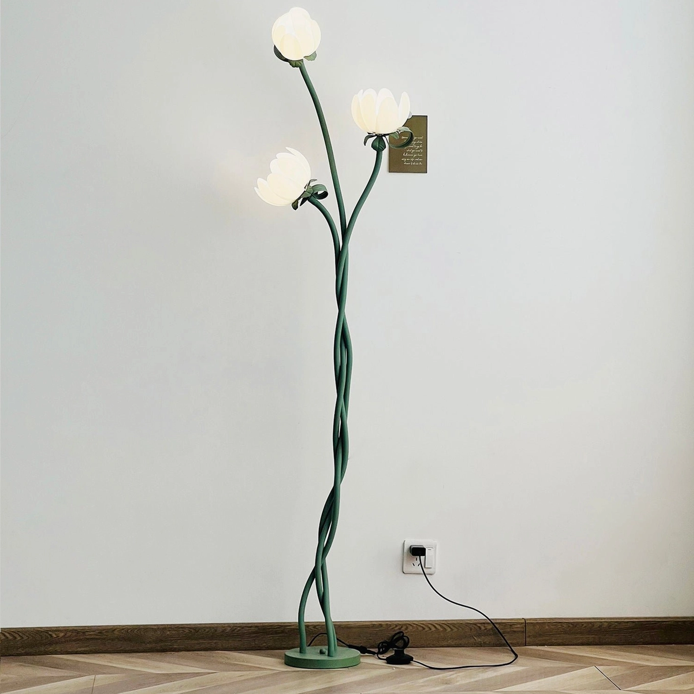 Magnolia floor lamp with lit white acrylic bloom shades casting warm ambient glow in modern living room with wooden flooring