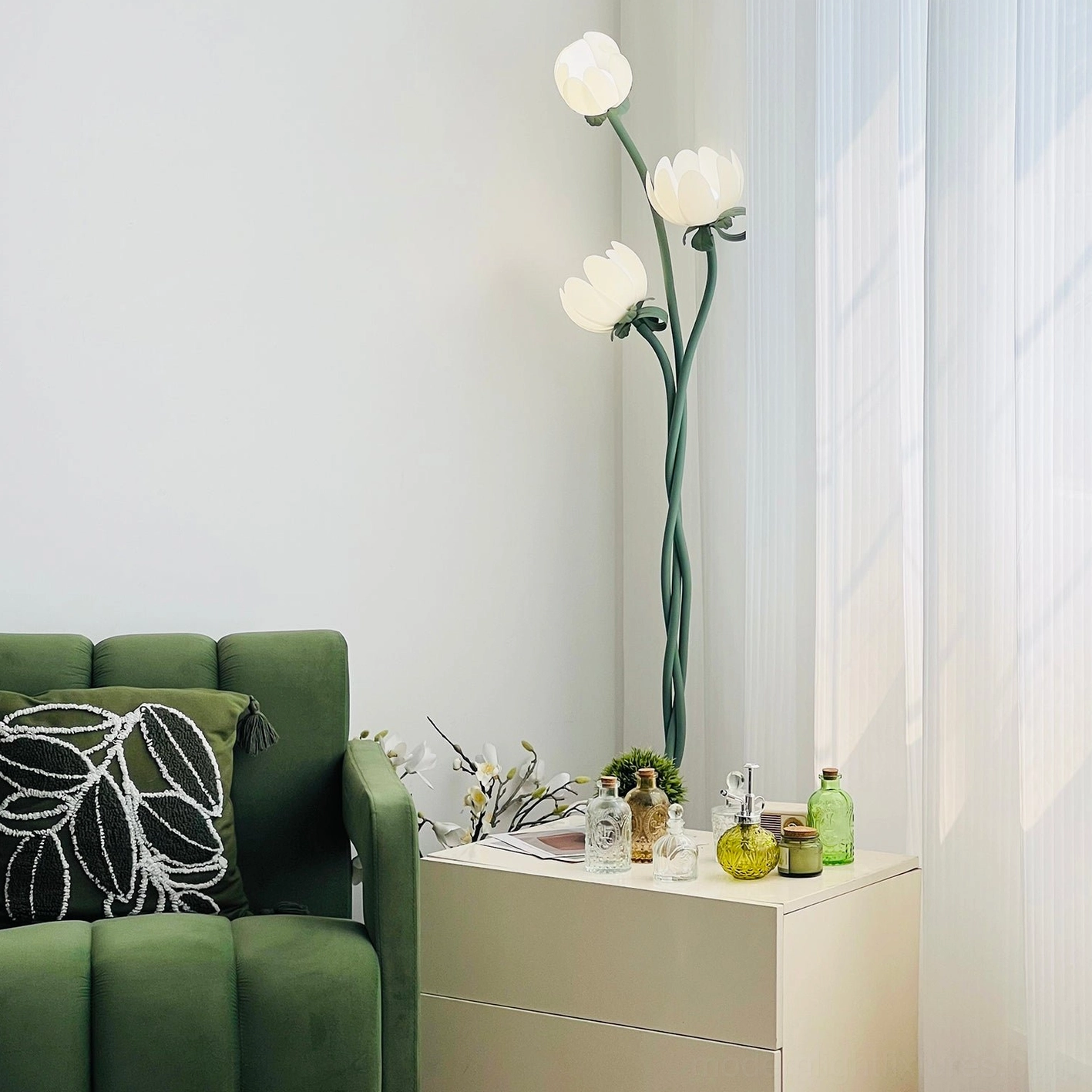 Magnolia bud floor lamp styled in Nordic minimalist living room with green sofa creating cohesive botanical decor scheme