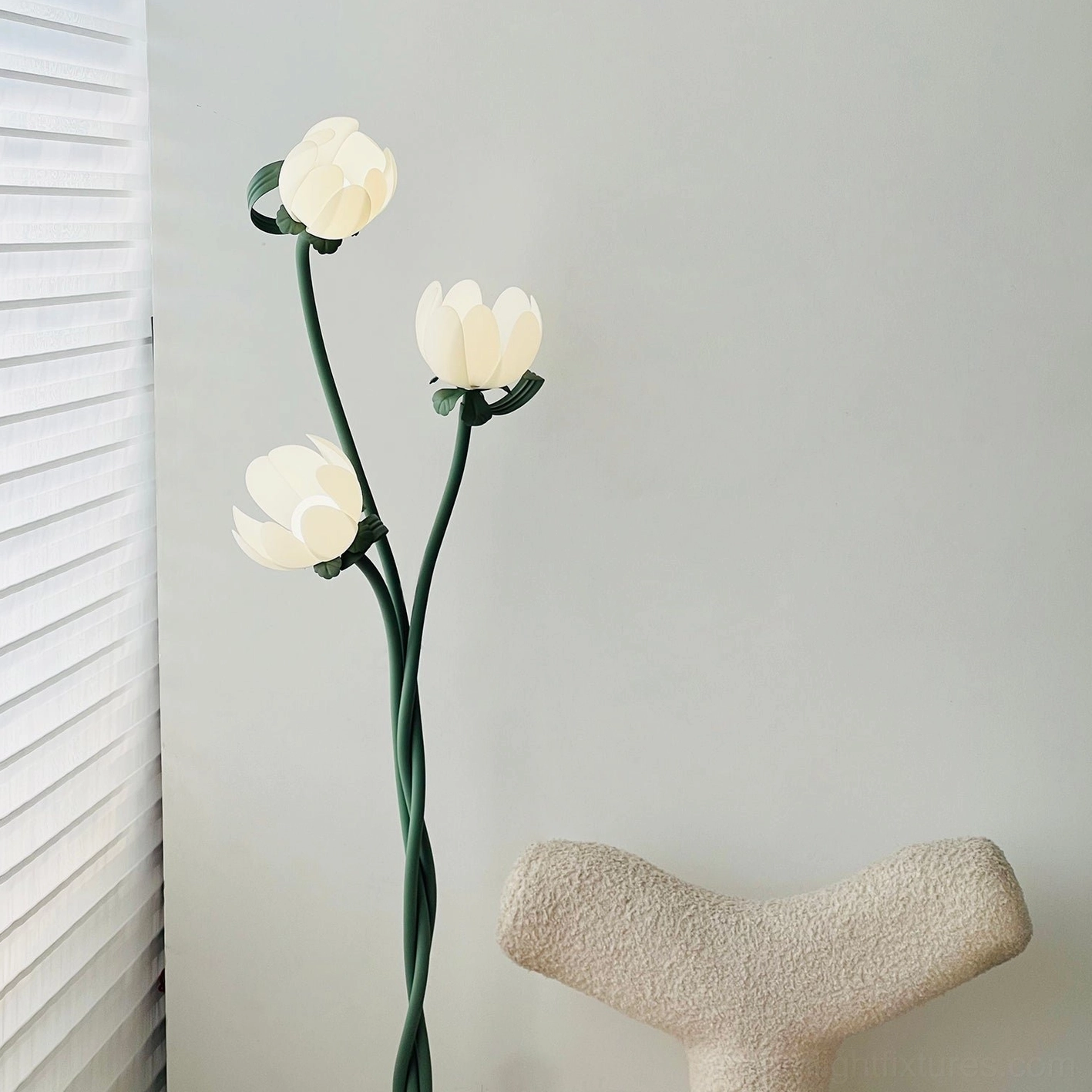 Three-bloom magnolia floor lamp in sunlit interior with decorative stool and louvered window creating warm ambiance