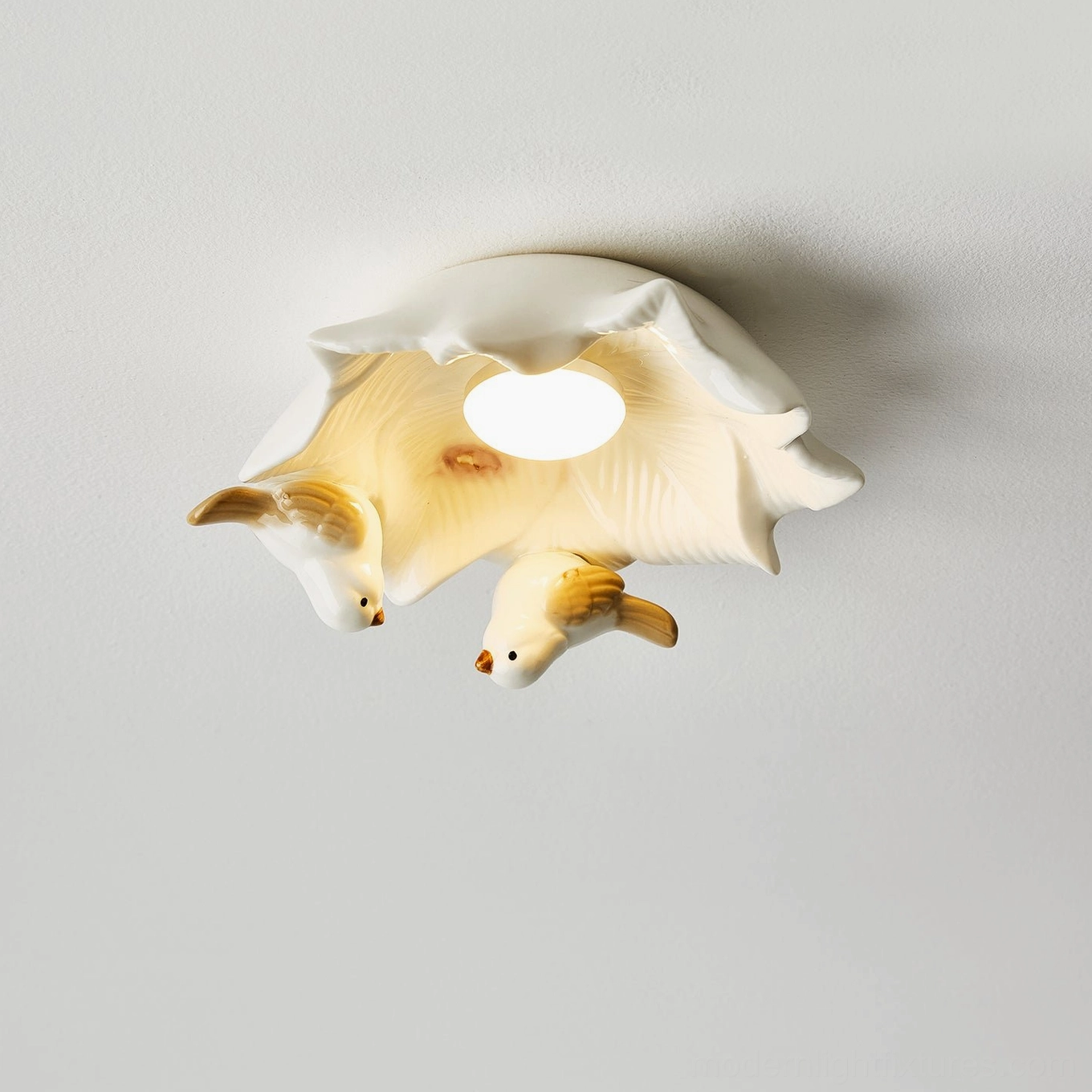 Front overhead close-up of Magnolia Nest modern ceiling lamp with two ceramic birds and illuminated magnolia bloom center