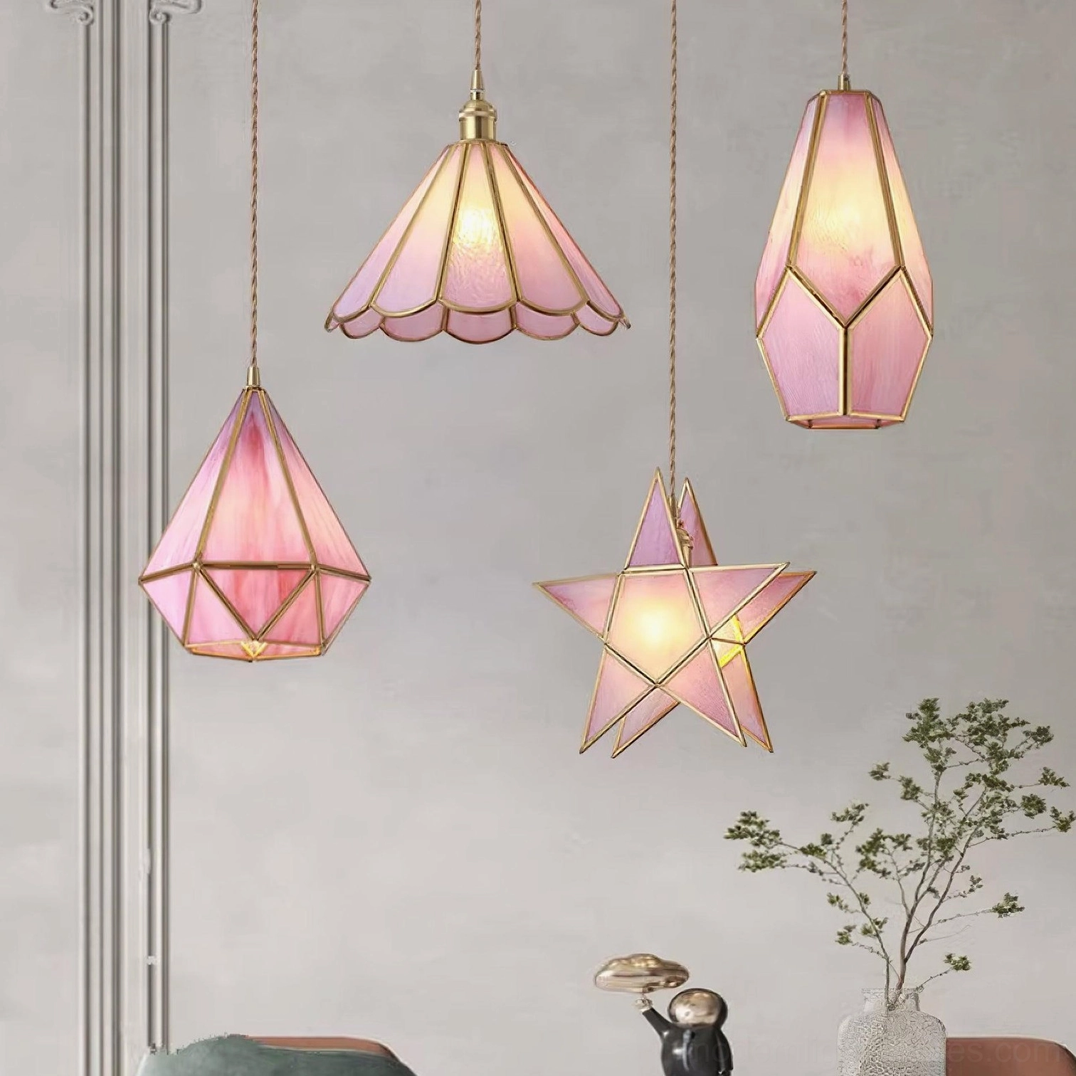 Collection of Maki glass pendant lights in pink, blue, and gold colors, minimalist living room setting