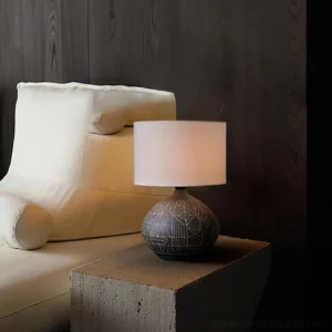 Ceramic sgraffito table lamp displayed on concrete side table in modern living room with dark wood wall