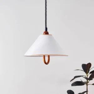 Adjustable pendant lamp in white and walnut color, rear oblique angle with decorative foliage backdrop
