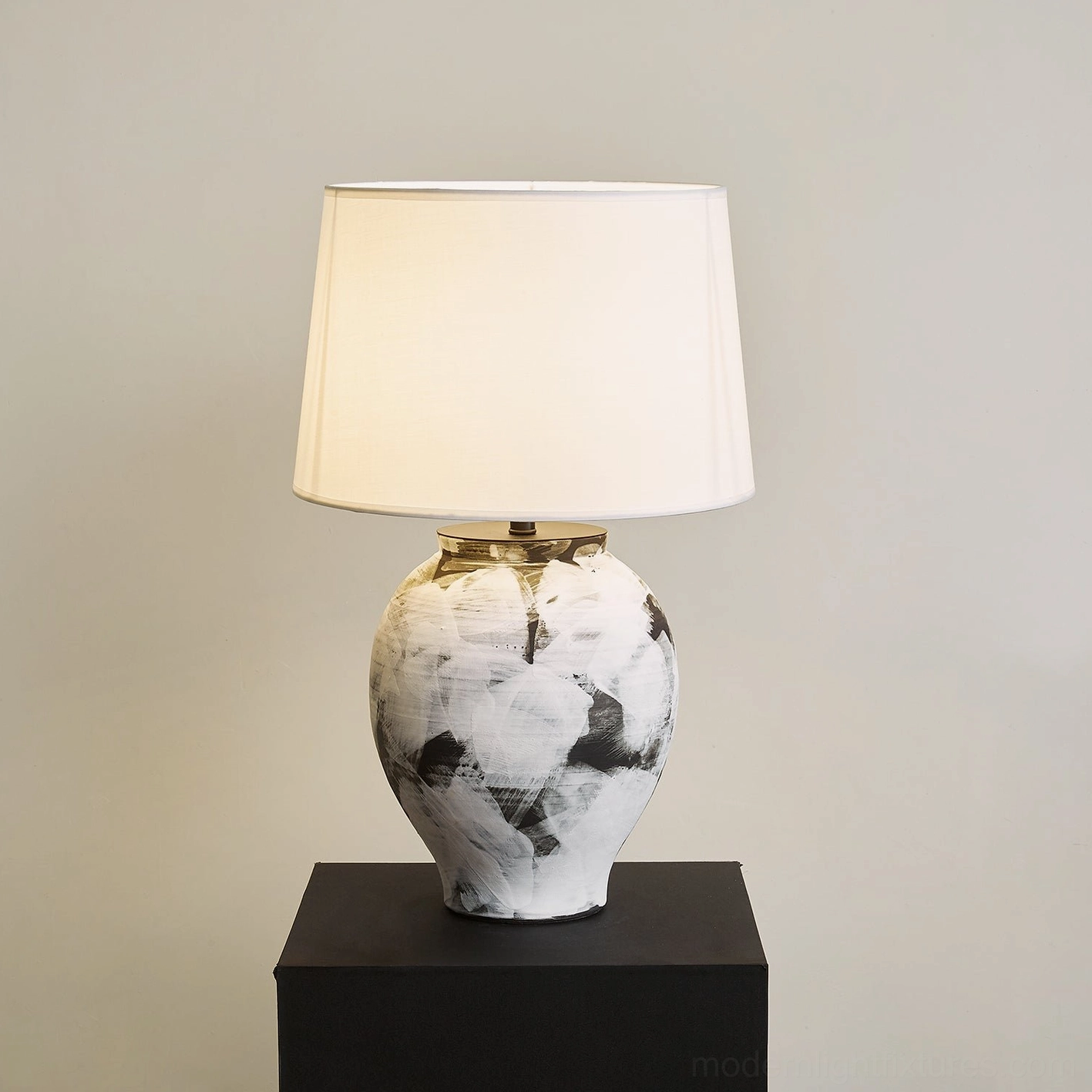 Illuminated Malta table lamp with hand-painted ceramic base at three-quarter angle showing urn silhouette