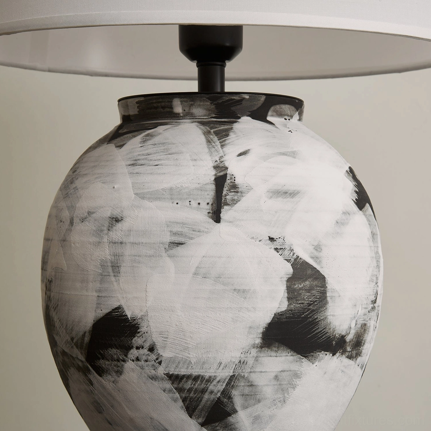 Close-up detail of Malta lamp ceramic base showing hand-painted black and white abstract brushstrokes and metal collar