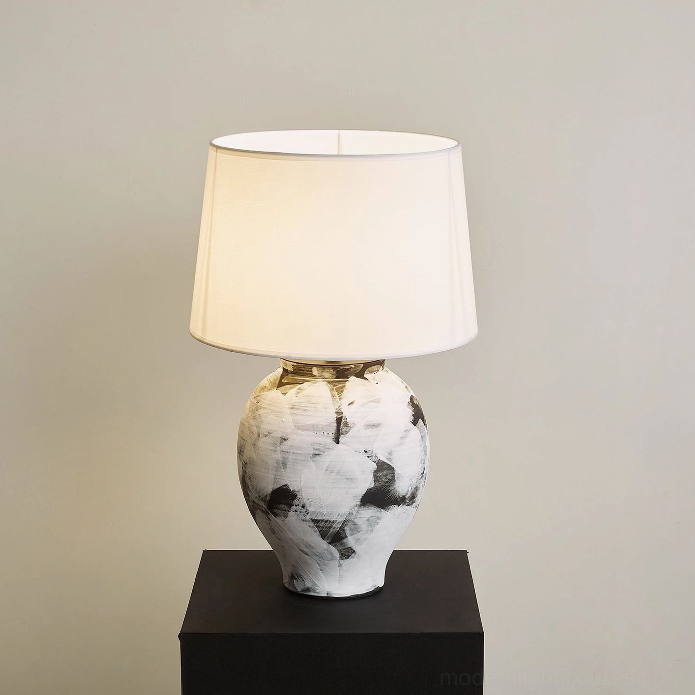 Malta table lamp right-angle view illuminated with warm light and white fabric lampshade